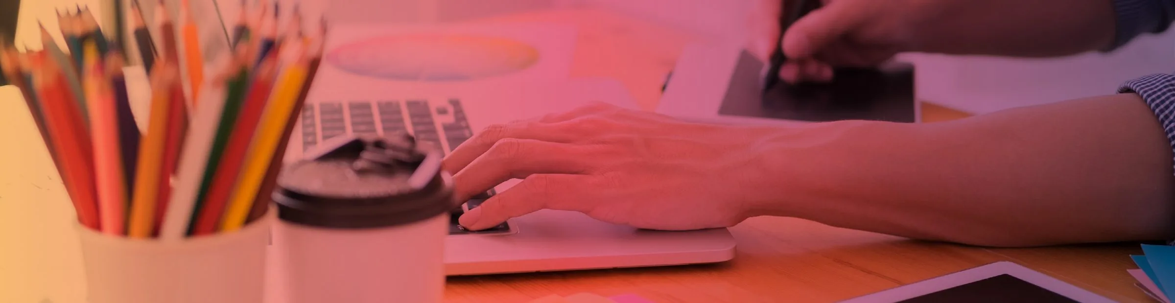 Arbeitsplatz mit Buntstiften, Laptop und Grafiktablett bei der Designarbeit