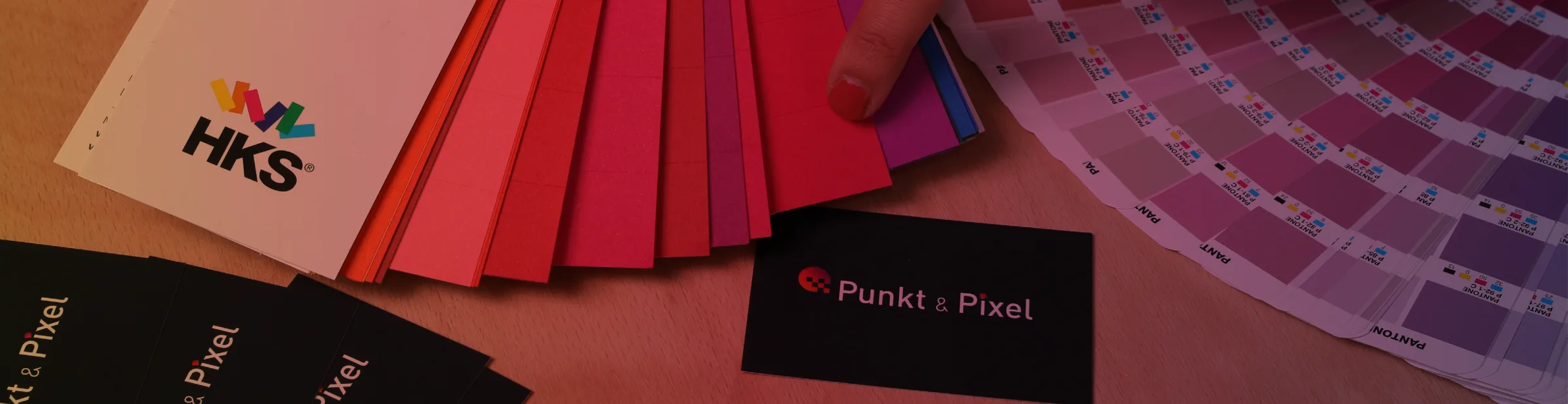 Farbfächer mit HKS- und Pantone-Farbmustern neben Visitenkarten von Punkt & Pixel